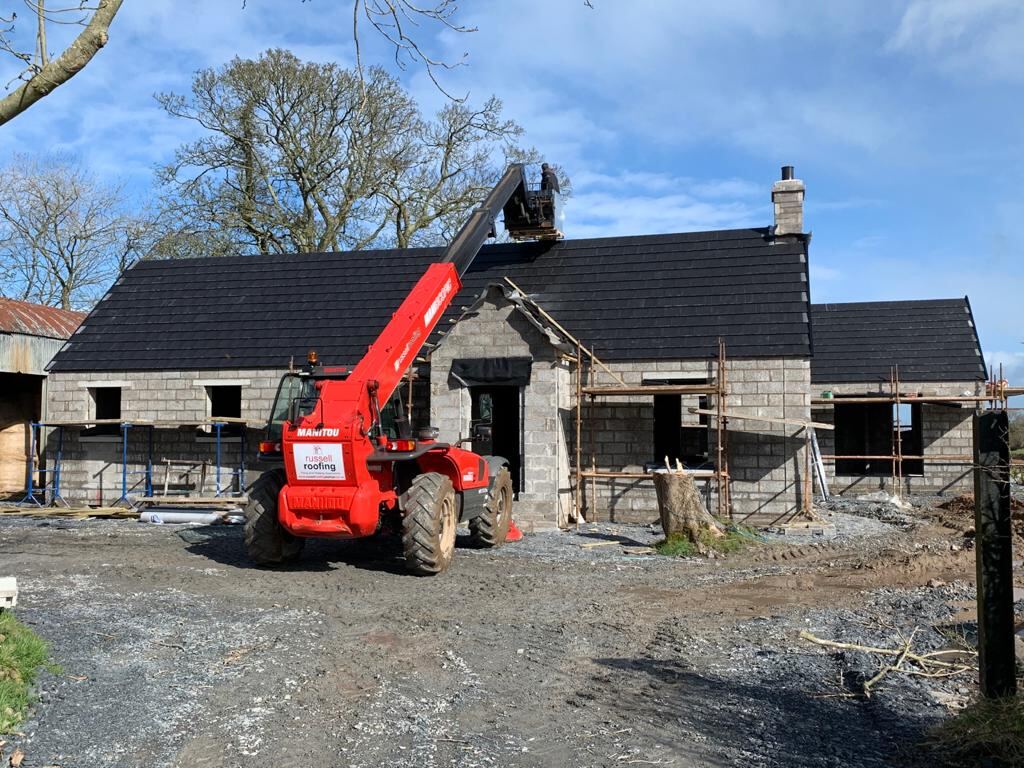 Stone cottage being re-roofed with telehandler lifting materials