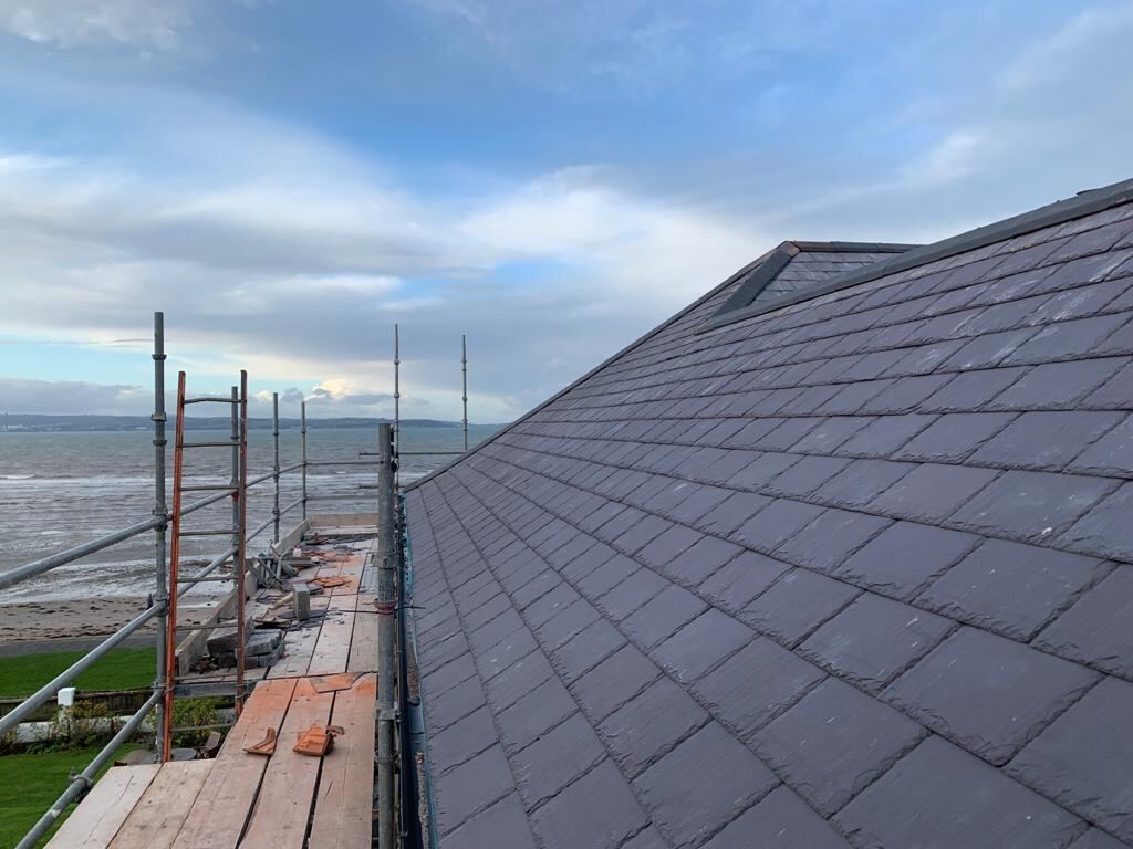 Long slate roof with scaffolding and a view out over the water