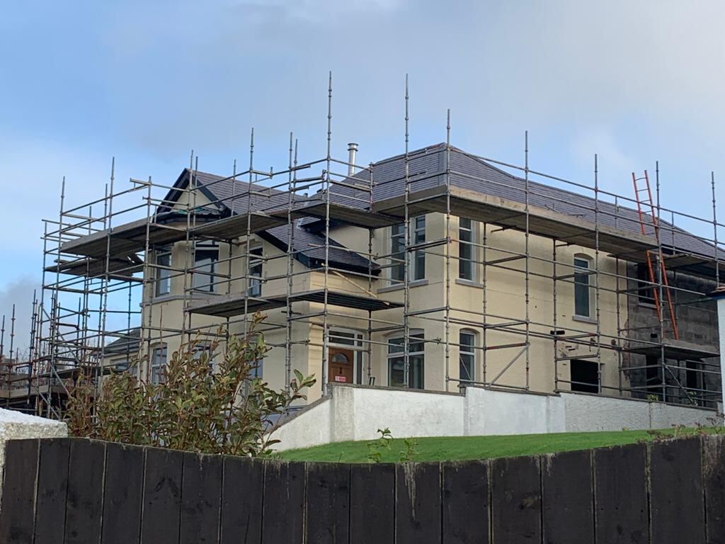 New build house under scaffolding with a freshly slated roof