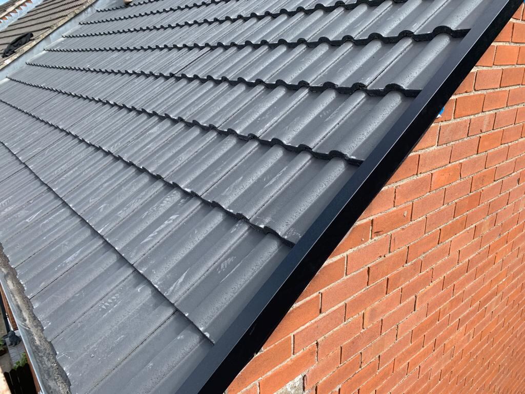 Close up of a newly tiled roof verge against red brick