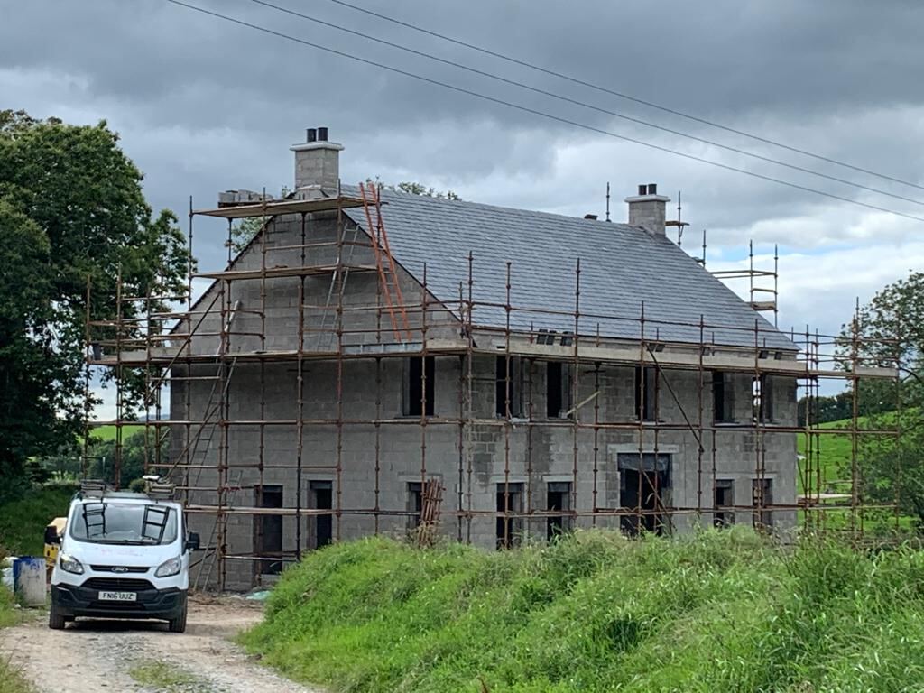 Two storey new build with slate roof under scaffolding